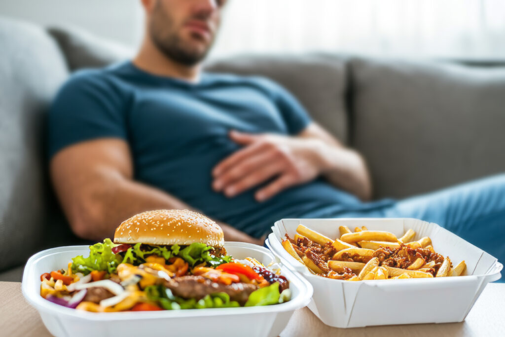Man experiencing stomach discomfort after eating fast food — unhealthy diet and gut health impact